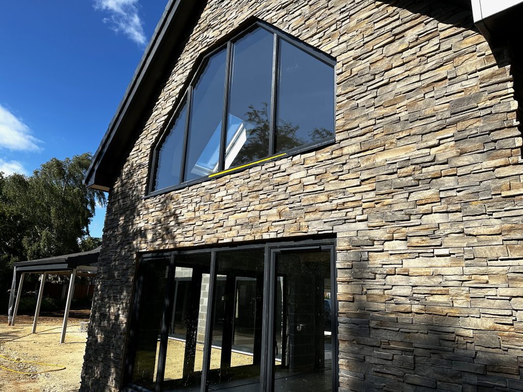 Stacked stone cladding installation on house exterior