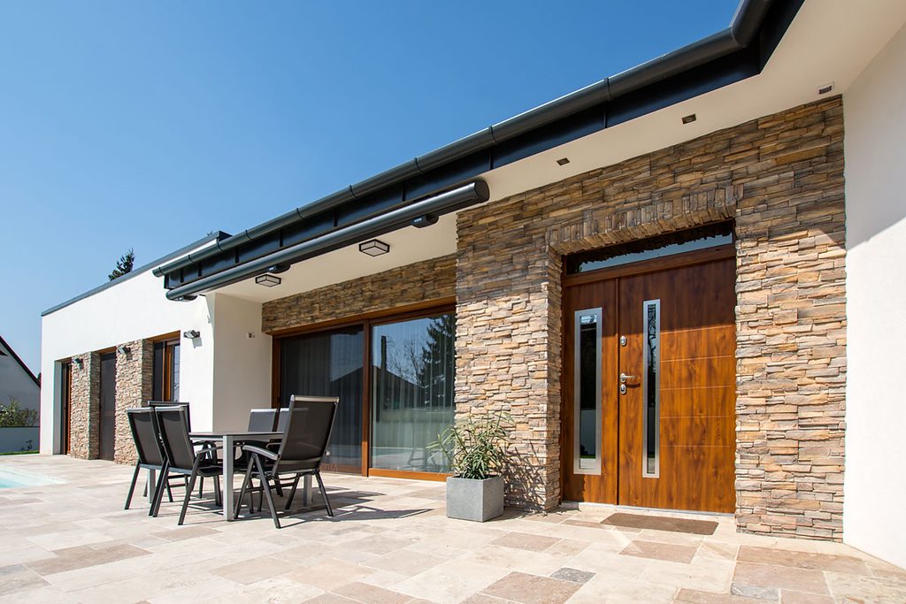 Grenada stone cladding contrasting with off-white render on house exterior