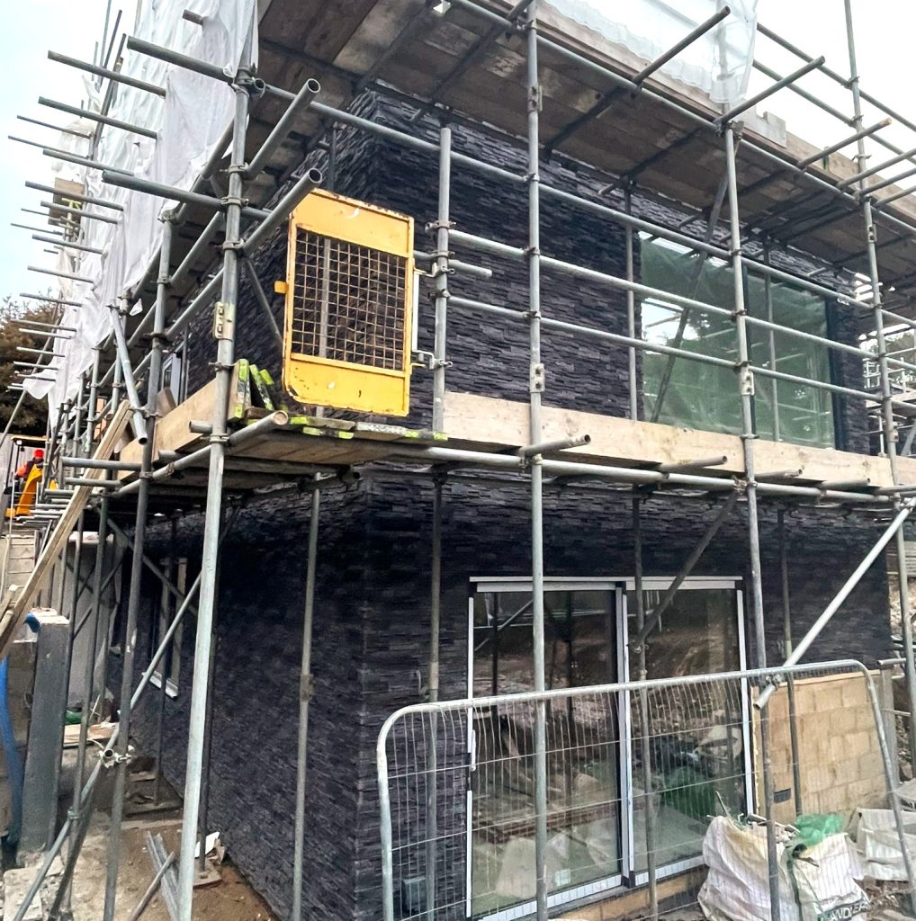 Stone cladding installation on house exterior during renovation